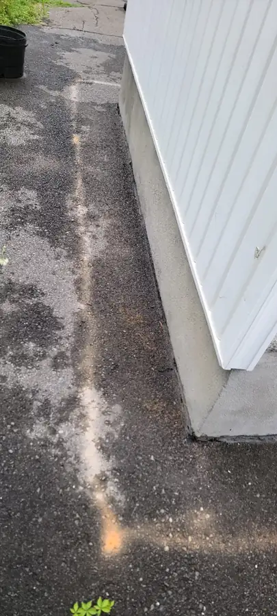 Ligne de coupe dans l'asphalte le long d'un revêtement blanc