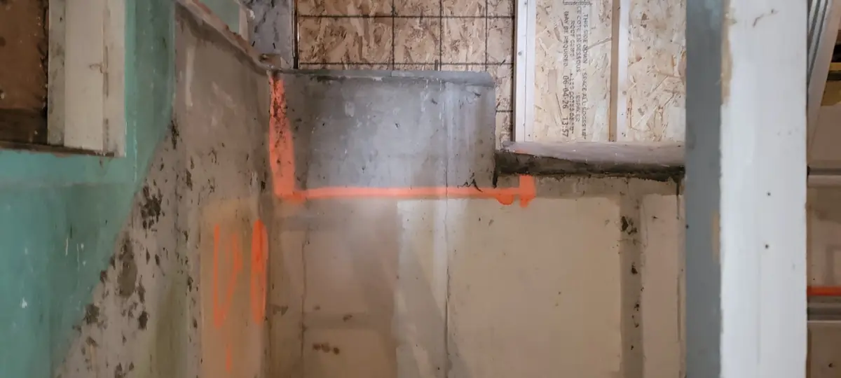 Tracé orange sur un mur de sous-sol pour le parcours de la plomberie