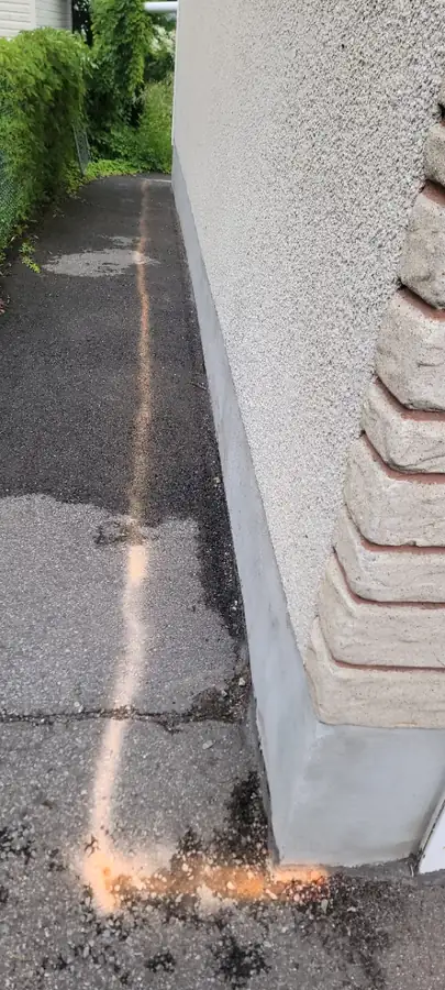 Trait de scie droit dans l'asphalte le long d'un mur de maison